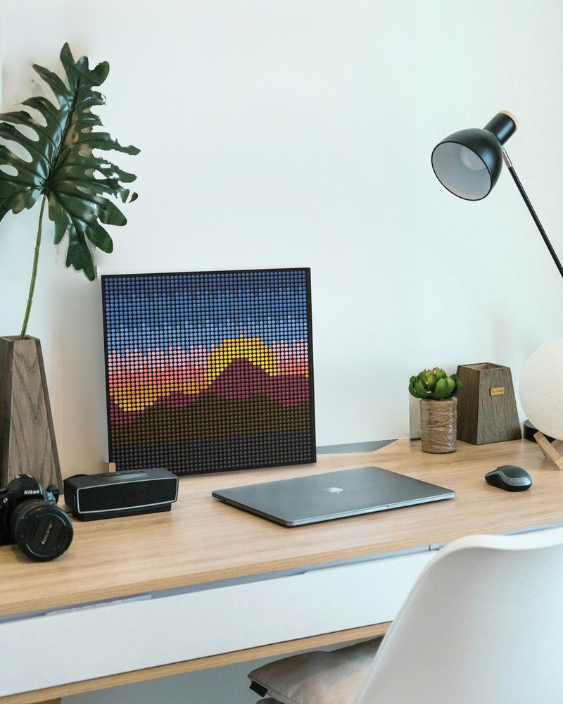 A mountain sunset mosaic leaning on a desk next to a laptop